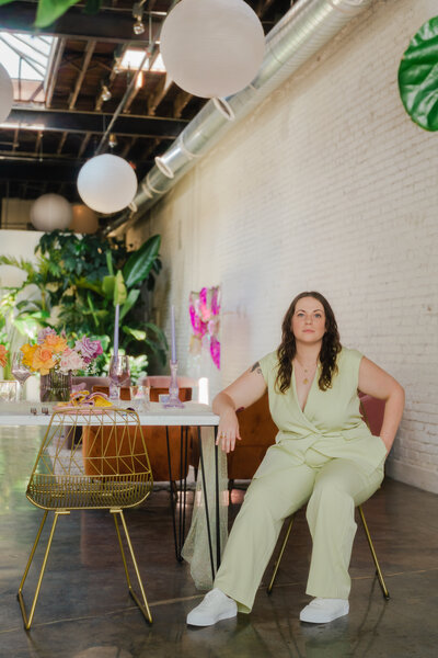 woman in a green jumpsuit sitting at a table