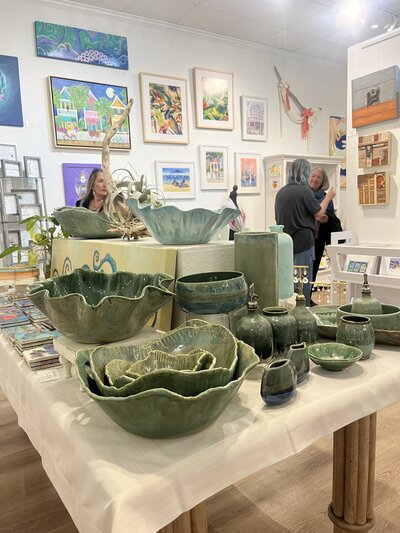 A table inside of Sacred Space Gallery in Key West, Florida displays fruit bowls, mugs, oil bottle and plates made by Jill Marie Pottery alongside other artwork by woman artists residing in Key West, FL