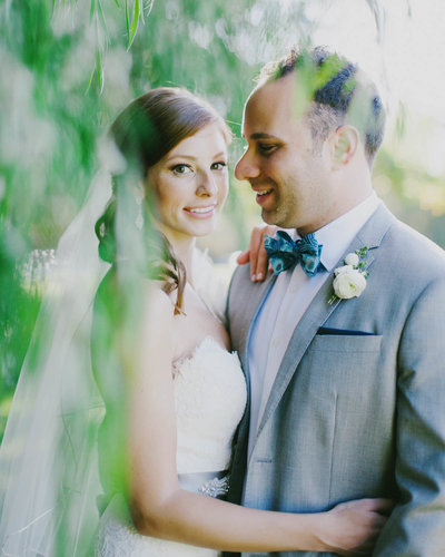 Groom smiling at Bride as Bride smiles at camera