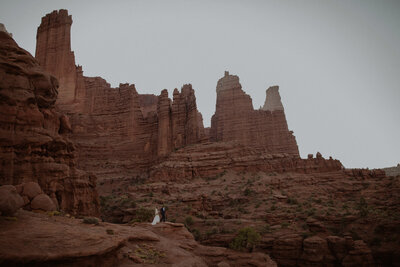 Bride and groom stand on a rock in the Moab, Utah desert