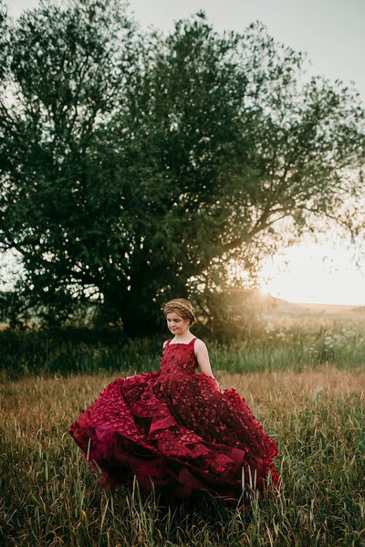 Girl in red dress in overgrown field with tree