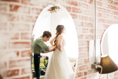 Person fixing bride's wedding gown