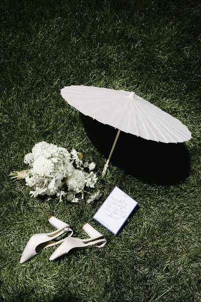 bridal bouquet, shoes, and umbrella in grass