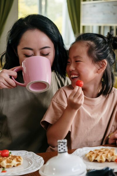 A mom drinking coffee at breakfast with her daughter. 
