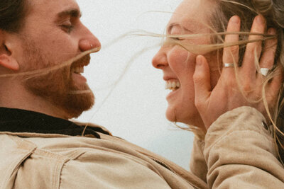 close up of couple laughing with man holding her face