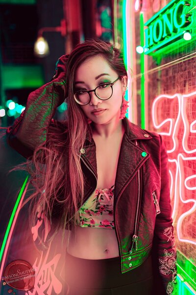 Kimmy Tran in glasses and leather jacket near neon lights