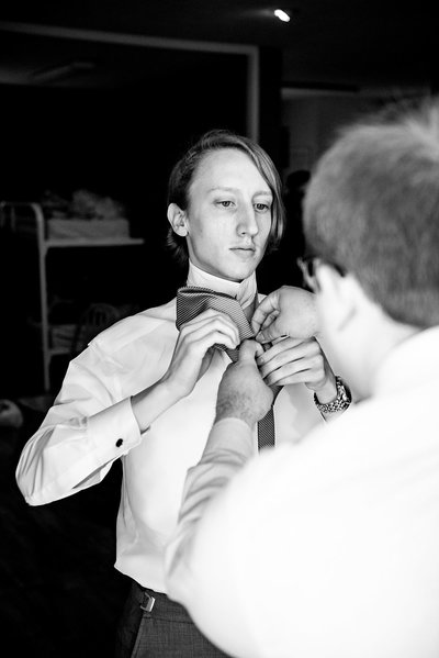 Black and White photo of Pat helping groom tie his tie