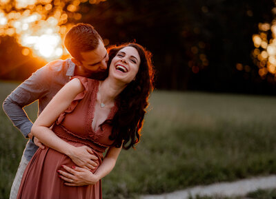 Schwangere, lachende Frau umarmt von Partner