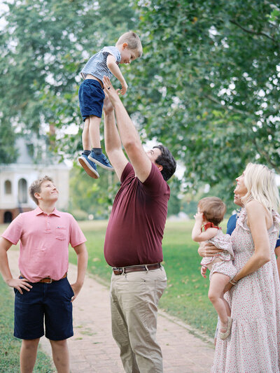 A man holding up a toddler surrounded by their family at a Richmond mini session by Katie Stansfield Photography.