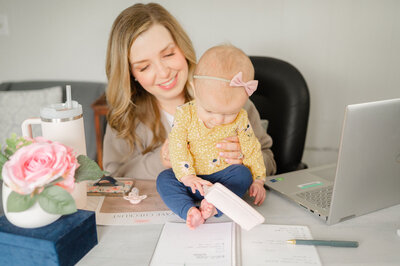 Erika sitting at her desk playing with her daughter