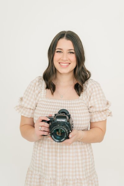 Ephe, a Connecticut and Massachusetts wedding photographer, smiles while holding her film camera at Nikki Estephan Studio.