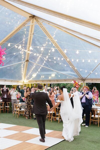 A newlywed couple walking hand in hand into their reception 
