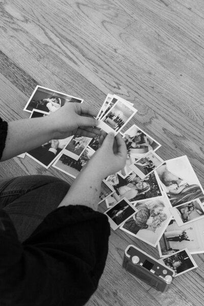 black and white image of photographer sorting through printed wedding photos