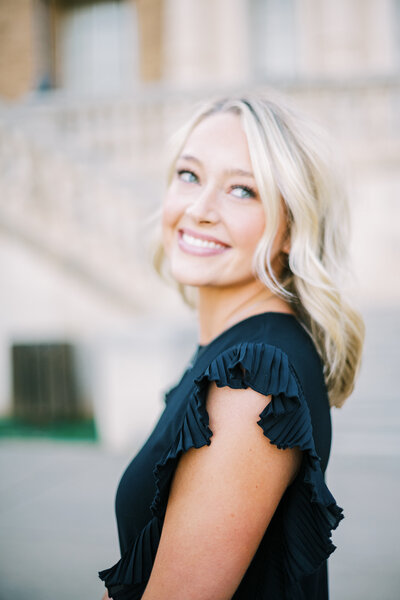 Close up image of girl with blonde hair and a black dress smiling