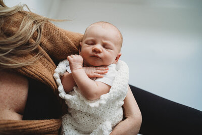 newborn baby girl in moms arms during boston newborn photo session