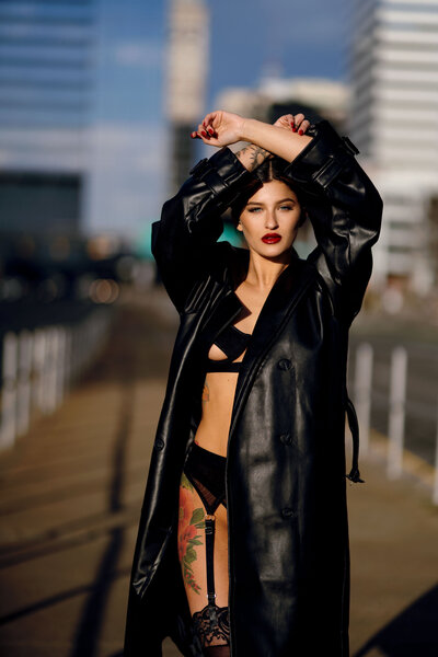 city fashion editorial of model in black trench coat and lingerie