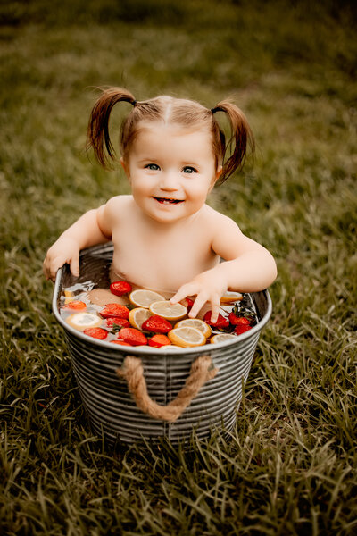 Liberty, Tx little girl sitting in a tub of water with fruit