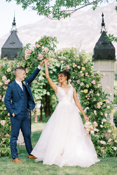 bride and groom twirl in front of floral ceremony arch at wadley farms in lindon, utah