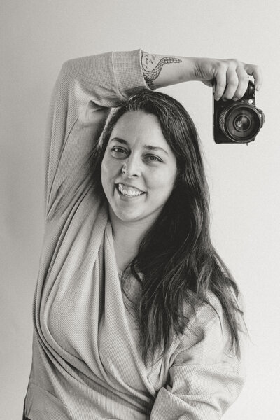 Black and white image of woman holding a nikon camera