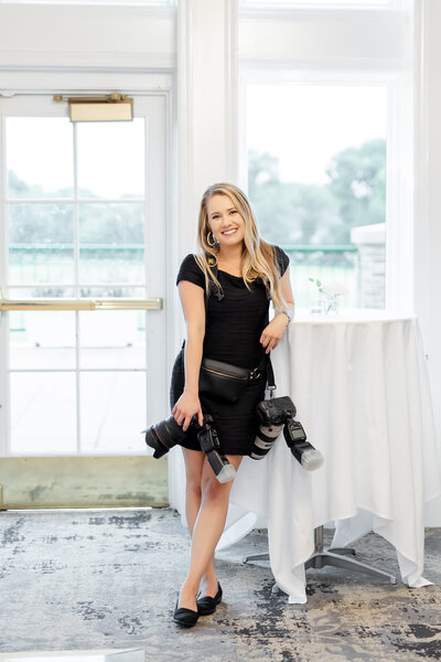 central florida wedding photographer lindsey white holding her cameras at a wedding