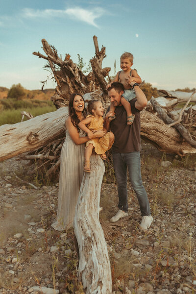Family standing together in front of a fallen tree at blue hour.