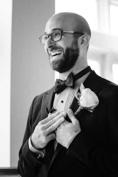 A person in a tux with his hands on his chest as he smiles.