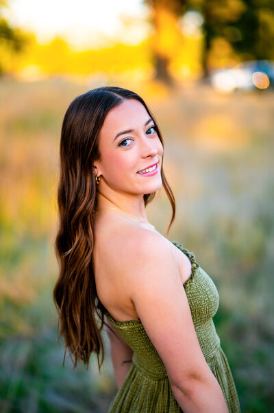 A colorful portrait of a Lake Washington High School girl. She is sitting in front of blue flowers in Federal Way, Washington. She is wearing a floral blue crop top and white skirt as an outfit for her senior photos.