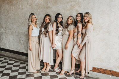 group of business ladies in neutral dresses standing together.