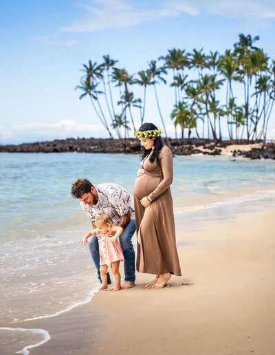 Family playing on beach for maternity photos, taken by big island Hawaii photographers at Hawaii Adventure Portraits