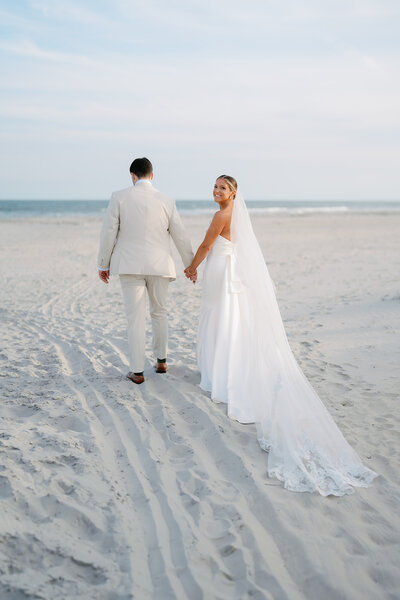 Bride and groom walking down the beach holding hands at Cape May wedding