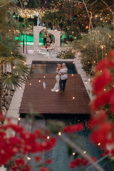 Kima wedding photo in Tulum - the couple dances on a floating wooden dance floor over sparkling water