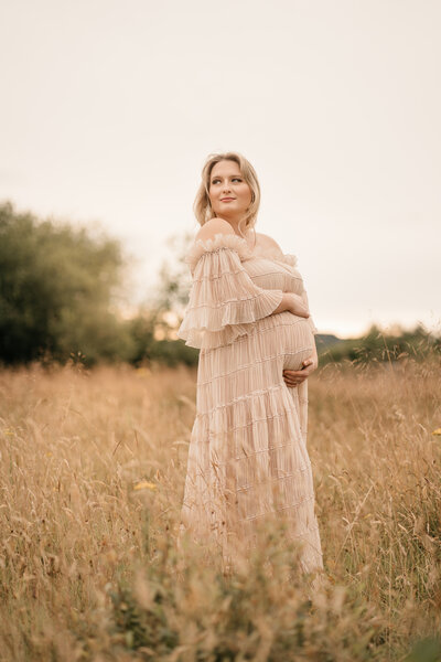 Photo of a couple standing outside at sunset. She is pregnant.