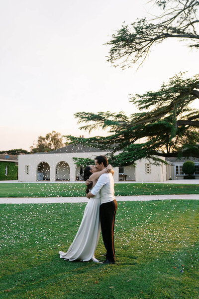 bride and groom hugging with confetti falling