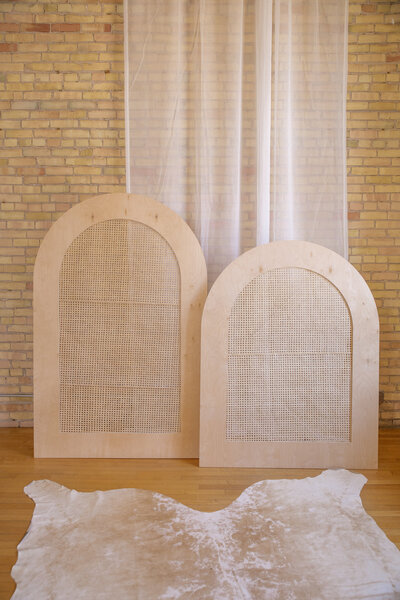 Two caned arches set up in front of a brick wall.