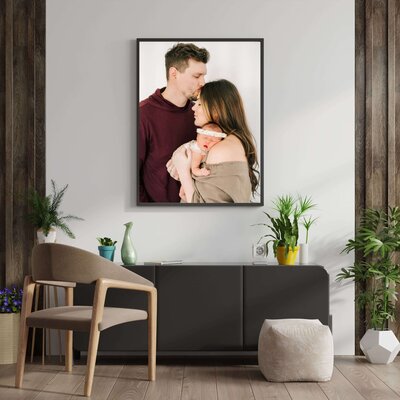 newborn photographer in Springfield MO captures a framed photo of husband kissing wife while holding baby girl