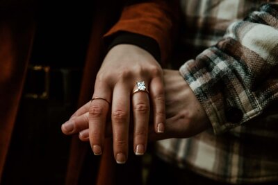 Celebrate your engagement with Everest Portraits, specializing in capturing the intricate details of your love, like this close-up shot of hands clasped together, featuring the elegance of an engagement ring set against the rustic charm of the Pacific Northwest.