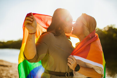 Lesbian Couple embracing beneath a rainbow flag in Albany New York