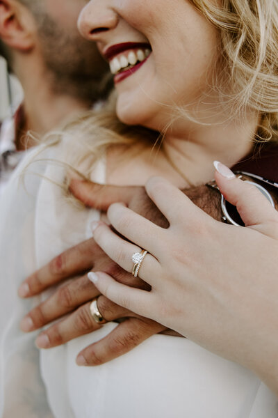 A close up of two people's hands resting on top of each other showing wedding rings 