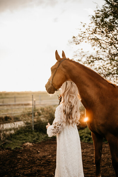 Bruid staat naast haar paard.