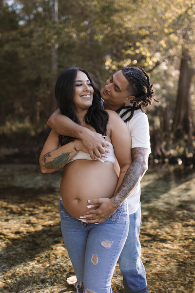 gainesville fl maternity photo dad embracing mom next to creek