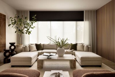 Minimalist Japandi living room featuring a natural marble coffee table, fresh organic greenery, and a custom U-shaped sectional for a grounded, serene aesthetic.