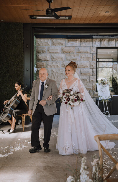 Bride walking down the aisle with dad on ceremony patio at Flores & Pine