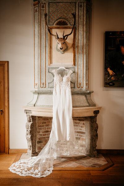 Een elegant beeld van een hangende trouwjurk in een klassieke setting, gefotografeerd met oog voor detail en sfeer.