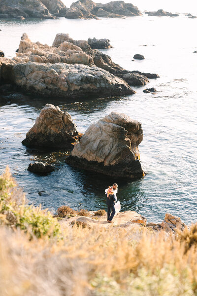 Couple embracing amongst the big sur cliff and ocean views