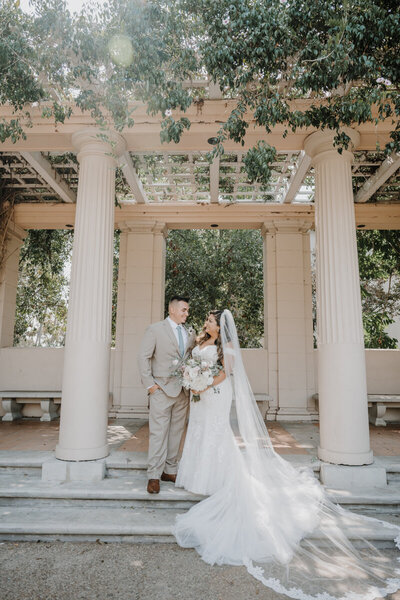 bride and groom looking at each other while standing under a pergola