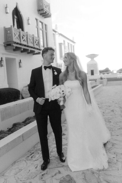 Bride and groom walking through Alys Beach neighborhood 