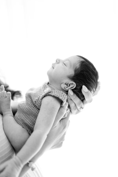 Newborn baby held on chest by Miami Newborn Photography