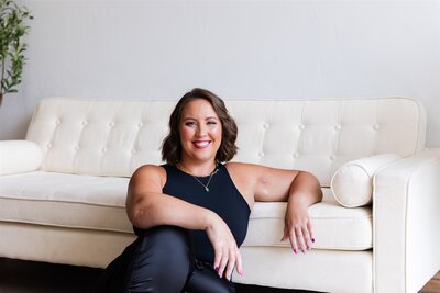 Trauma recovery speaker, Kathryn Konicek, smiling and leaning against a couch