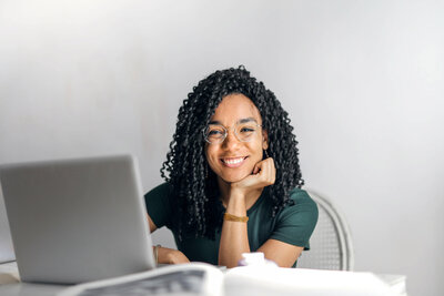 Jessica wearing a white blazer, smiling as she writes in her planner