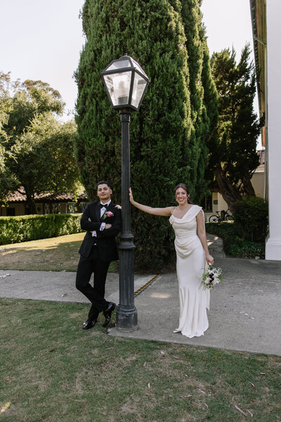 Bride and groom leading on a lamp post.